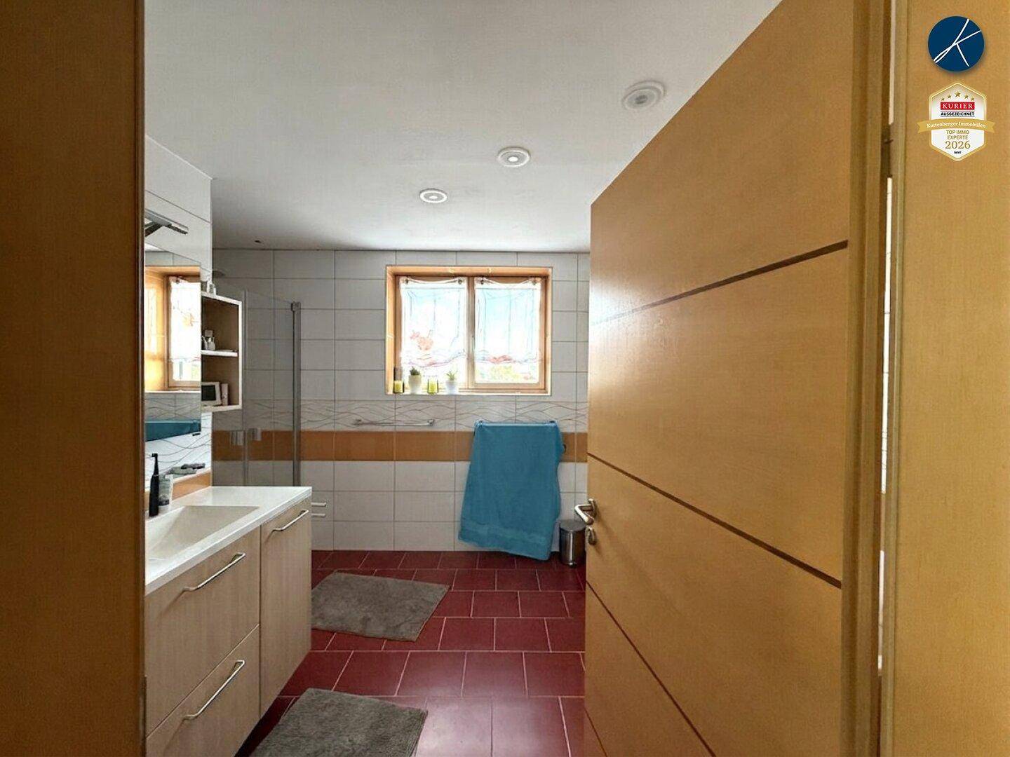 Badezimmer mit Fliesenboden, Fenster und modernem Waschtisch mit Unterschrank.