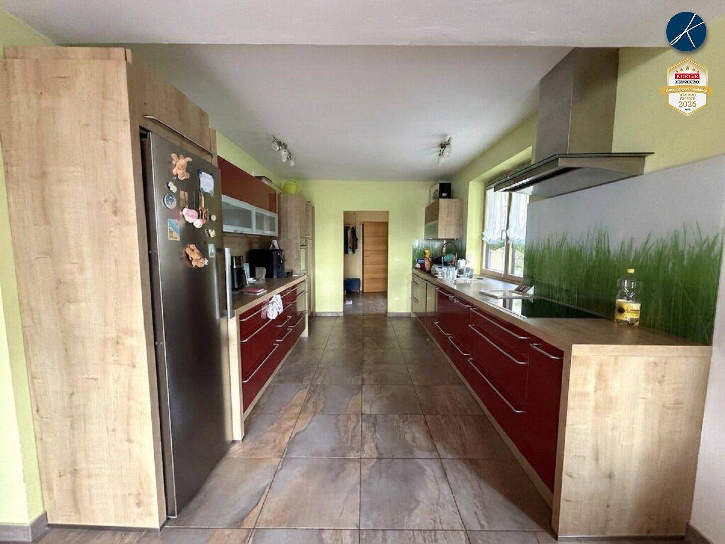 Moderne Küche mit roten Hochglanzfronten, Holzdetails und Fliesenboden.