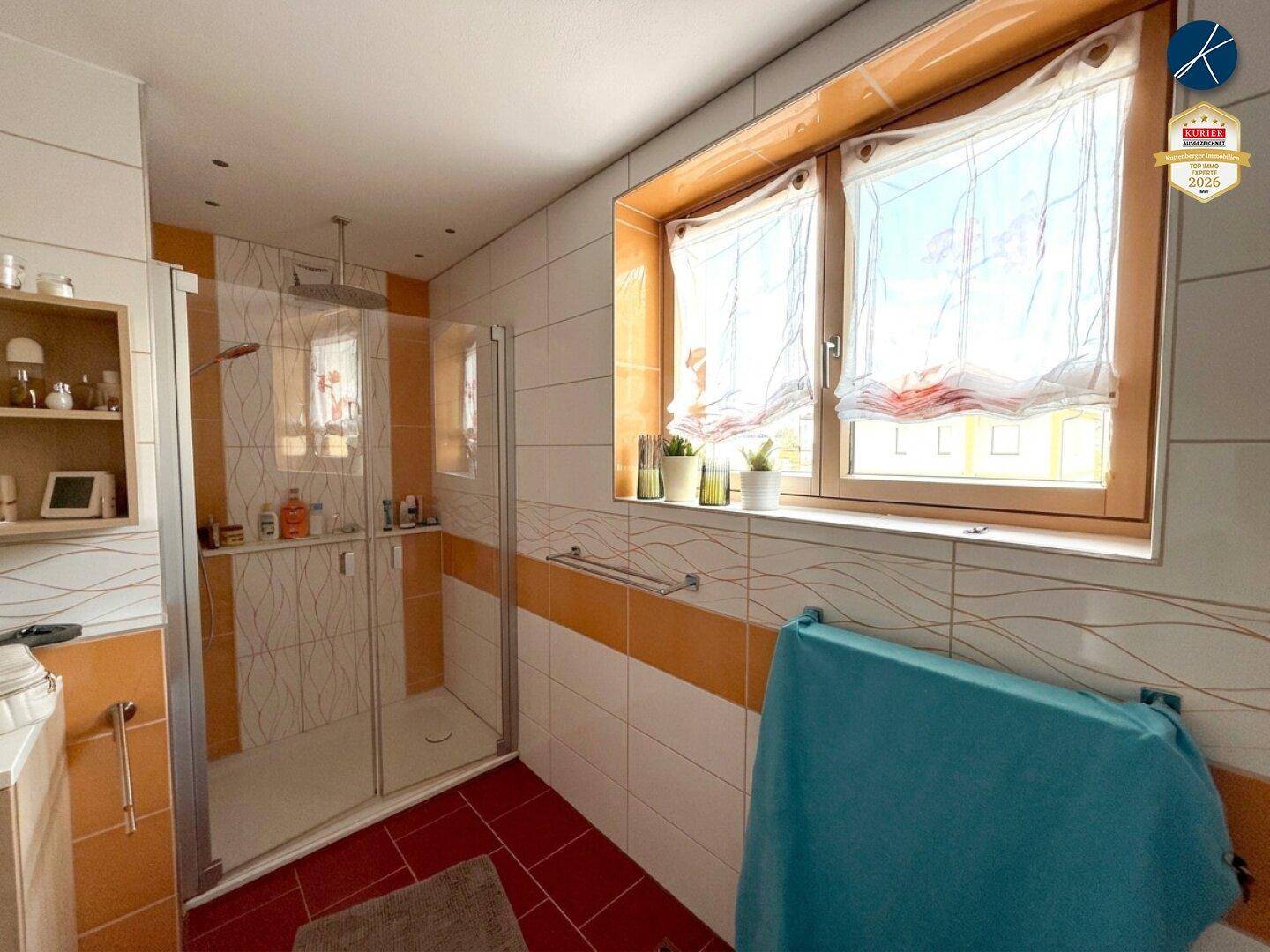 Modernes Badezimmer mit großer Duschkabine, Fenster und farbigen Fliesen.