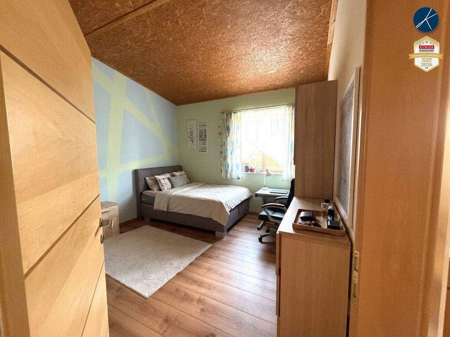 Helles Schlafzimmer mit Einzelbett, Schreibtisch und Holzboden.