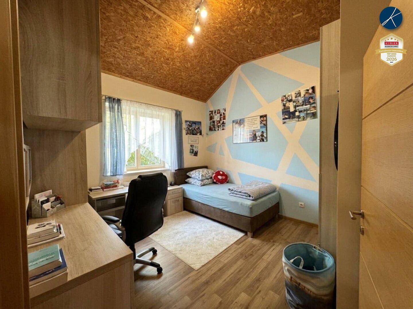Kinderzimmer mit Schreibtisch, Bett und kreativer Wandgestaltung.