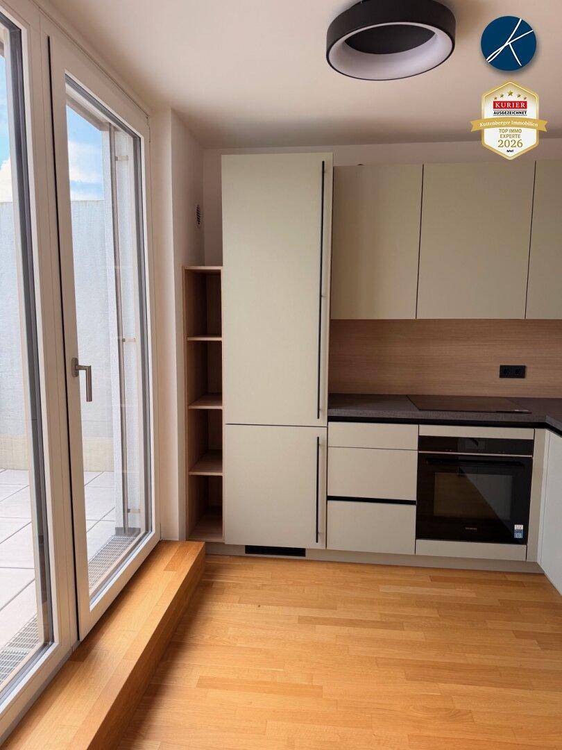 Helle Küche mit modernen Schränken und direktem Zugang zur sonnigen Dachterrasse.
