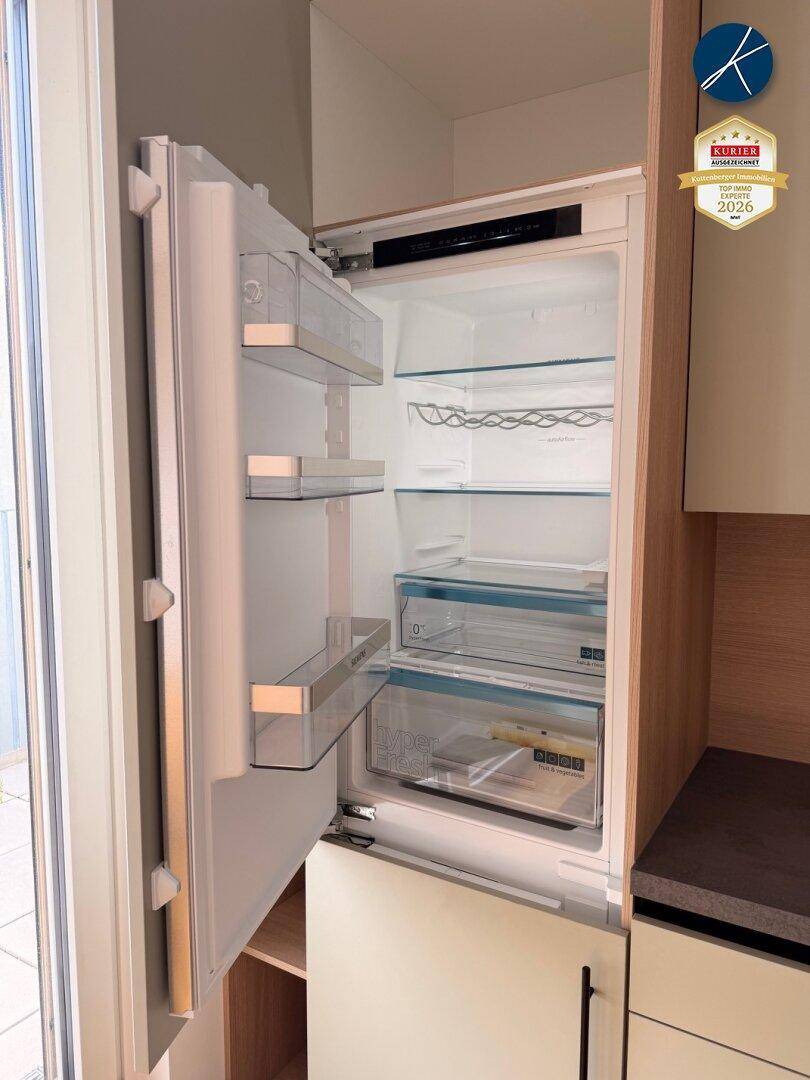Integrierter Kühlschrank mit mehreren Fächern und Glasablagen in der modernen Küche.