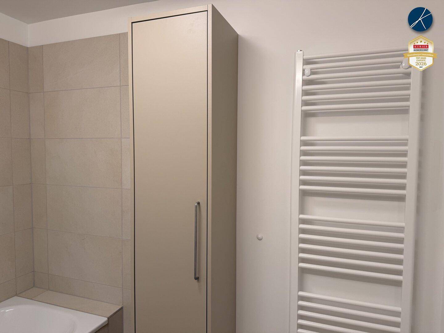 Badezimmer mit hohem Schrank und Handtuchheizkörper, bietet zusätzlichen Stauraum.