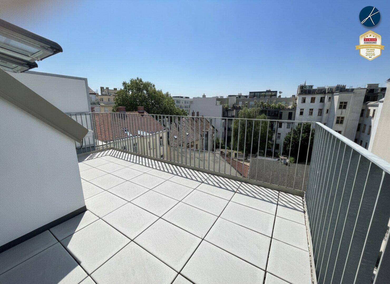 Geräumige Dachterrasse mit hellen Fliesen und Metallgeländer, bietet einen weiten Stadtblick.