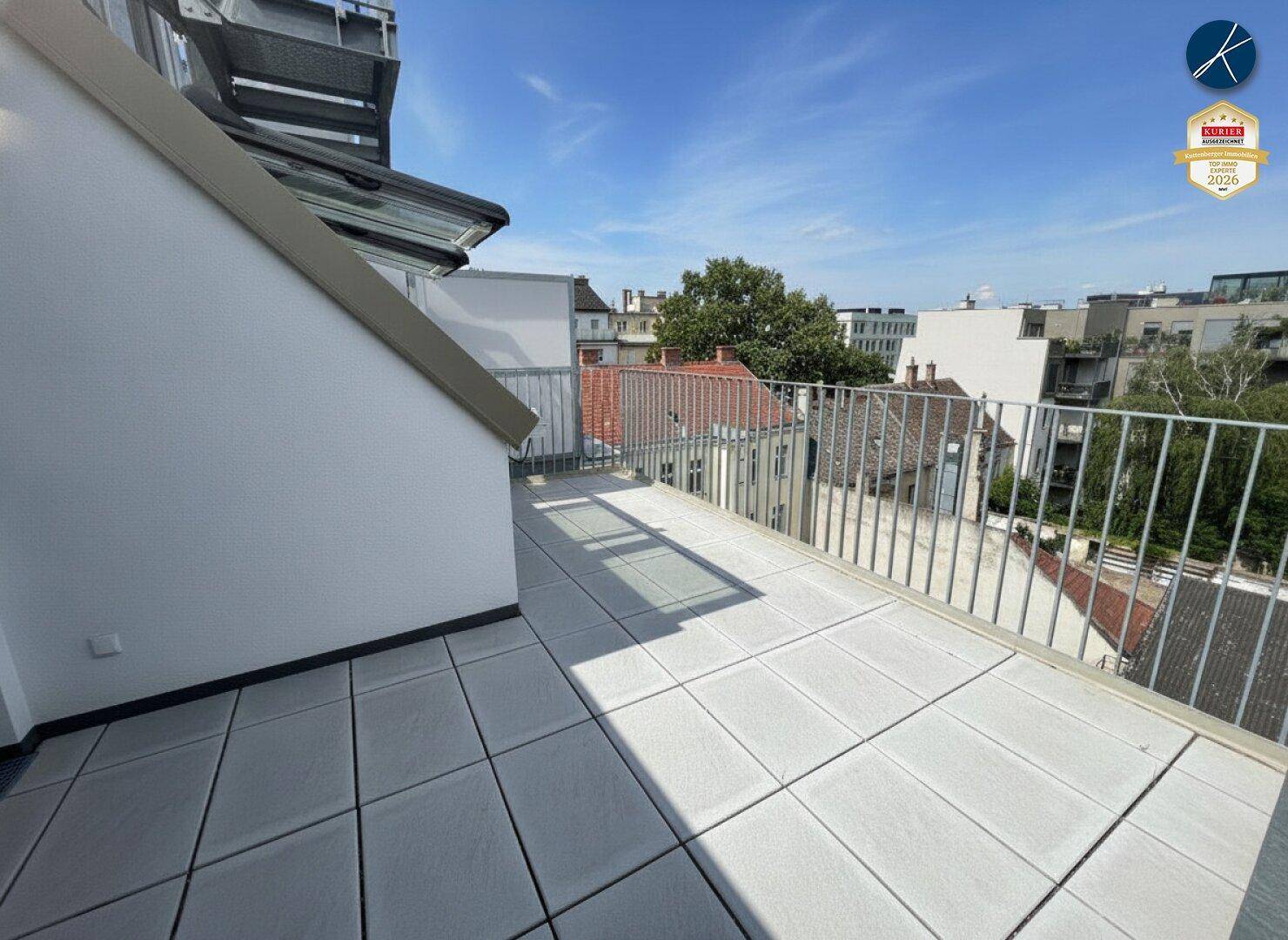 Geräumige Dachterrasse mit hellen Fliesen und Metallgeländer, bietet einen weiten Stadtblick.