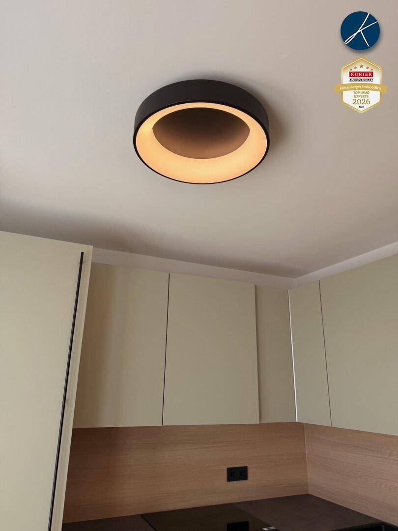 Moderne runde Deckenleuchte über den Küchenschränken, sorgt für angenehmes Licht.