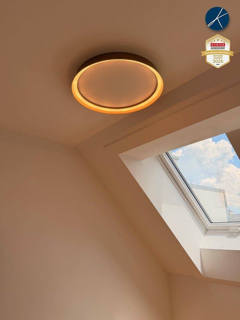 Moderne Deckenleuchte und ein Dachfenster sorgen für eine helle und angenehme Atmosphäre.