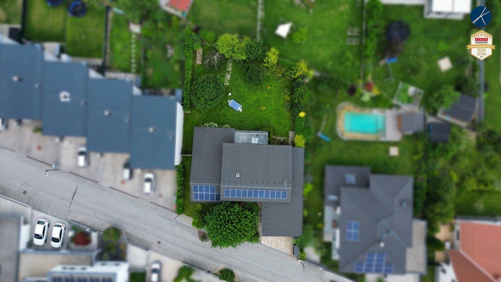 Luftaufnahme des Hauses mit Solaranlage auf dem Dach und umliegenden Wohngebieten.