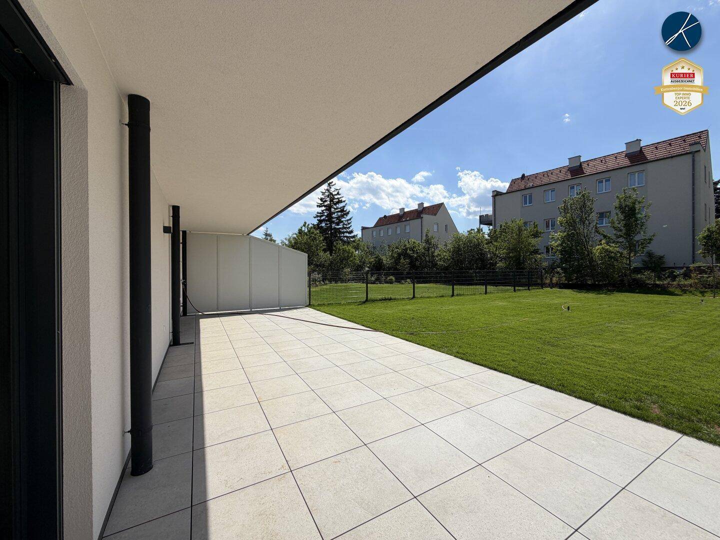 Weitläufige, geflieste Terrasse mit direktem Zugang zum Rasen und Blick auf die Umgebung.