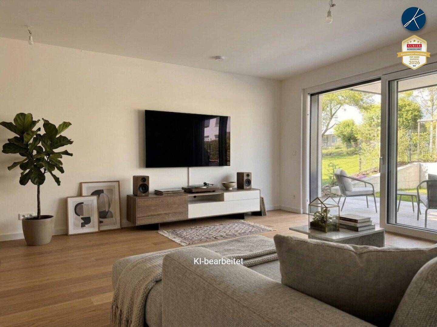Helles Wohnzimmer mit Holzboden, großem Fernseher und Zugang zu einer Außenterrasse.