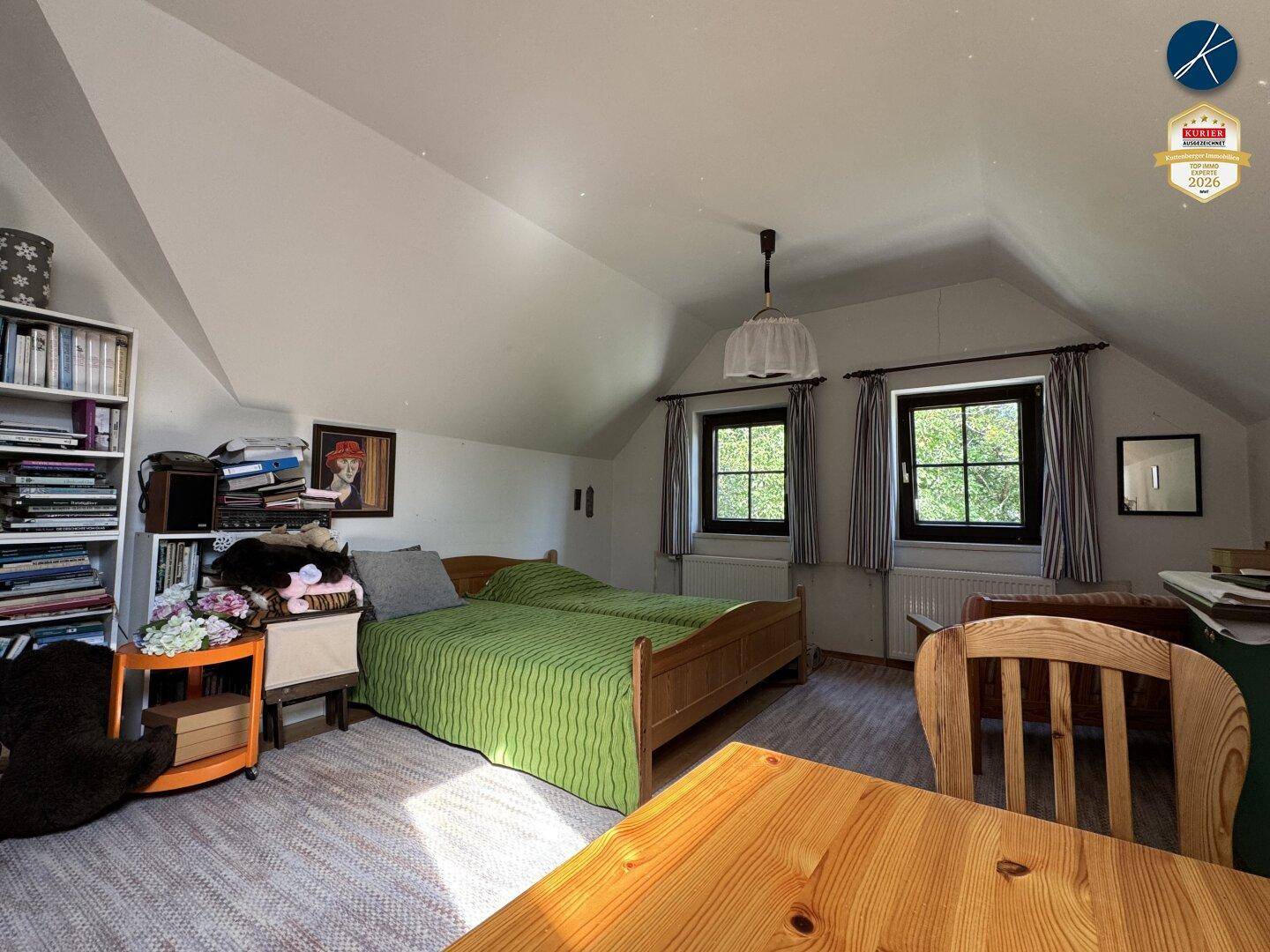 Schlafzimmer im Dachgeschoss mit zwei Einzelbetten, Bücherregal und Dachschräge.