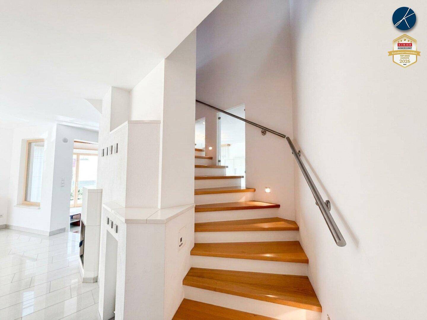 Elegante Holztreppe mit Edelstahlgeländer, die die verschiedenen Ebenen des Hauses verbindet.