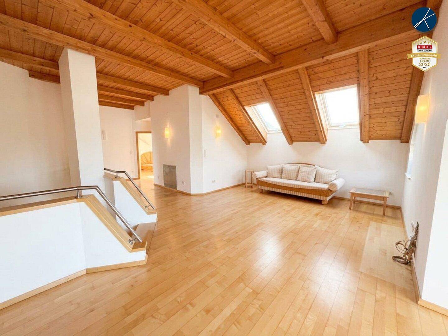 Geräumiger Dachgeschossraum mit Holzbalkendecke, Dachfenstern und hellem Holzboden.