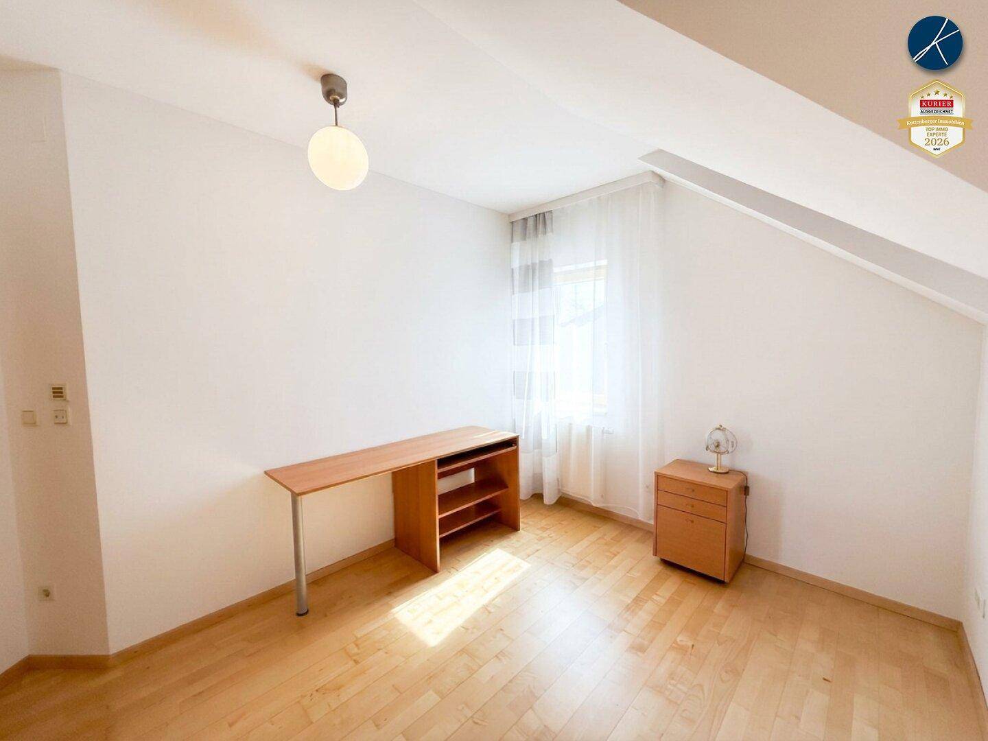 Helles Schlafzimmer mit Holzboden und schrägen Wänden im Dachgeschoss, ideal als Kinderzimmer.