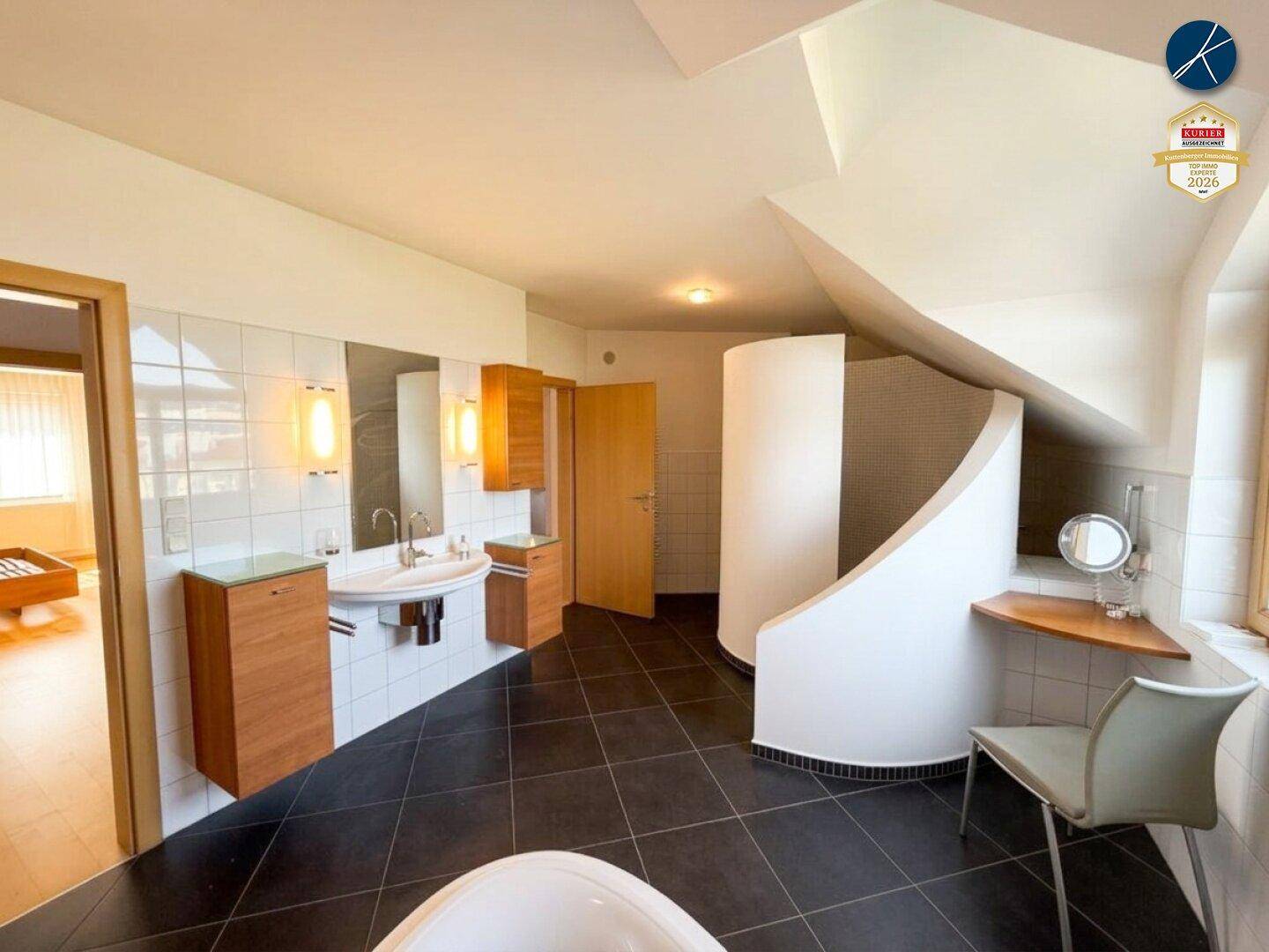 Großes Badezimmer mit Doppelwaschbecken, dunklen Fliesen und moderner Duschkabine.