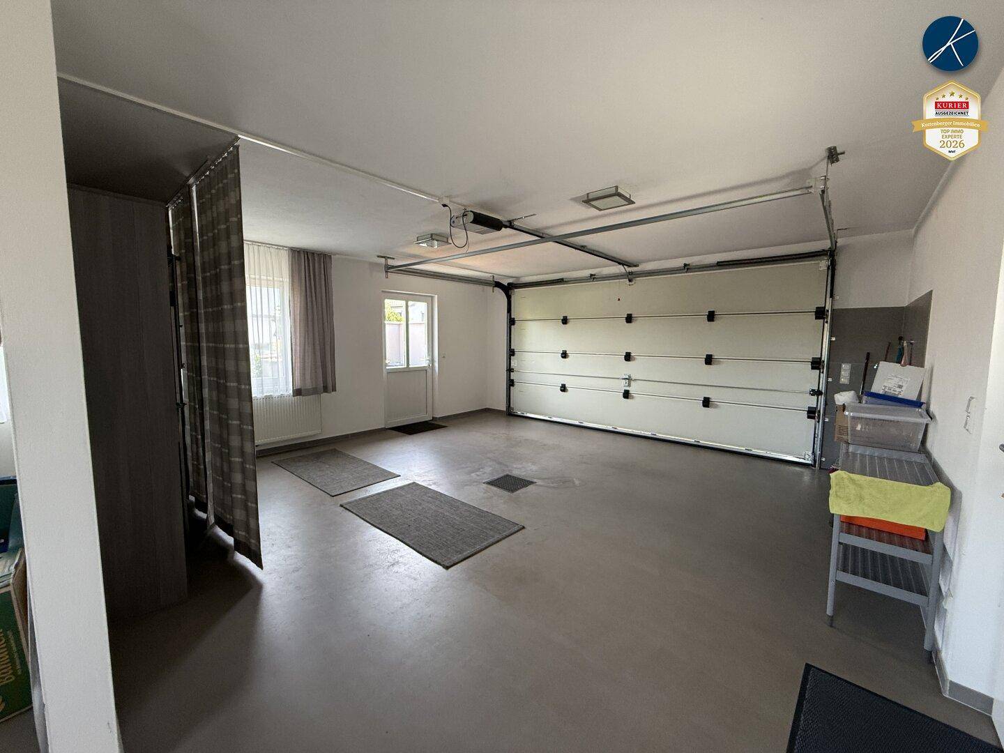 Geräumige Garage mit Sektionaltor, Fenstern und direktem Zugang zum Haus.