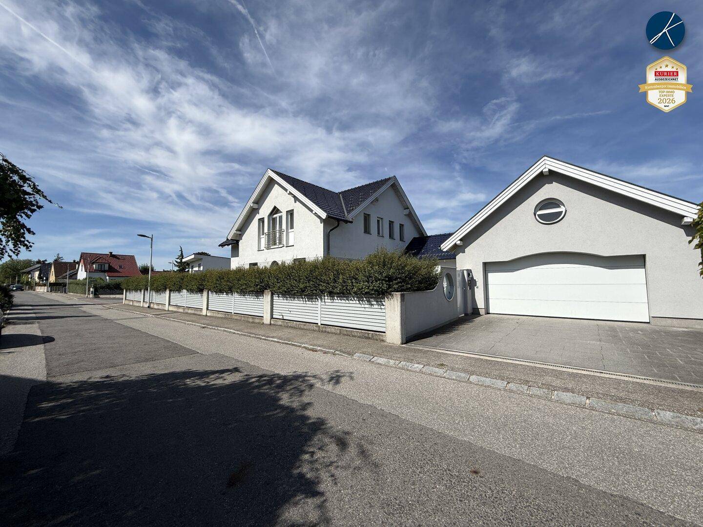 Ansicht des Hauses und der Garage von der Straße mit gepflegtem Vorgarten.