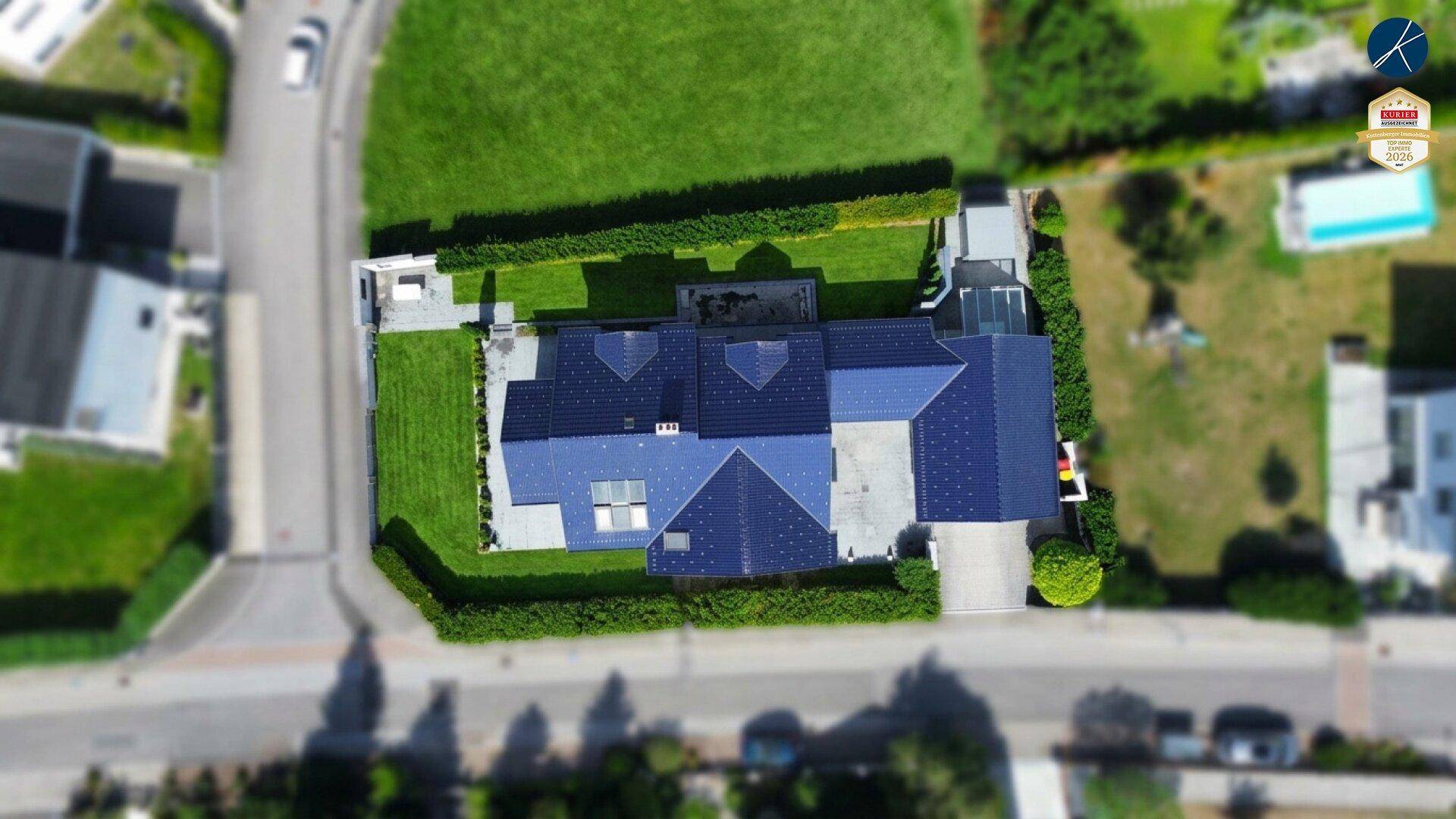 Luftaufnahme des Einfamilienhauses mit Solaranlage auf dem Dach und großem, grünem Garten.