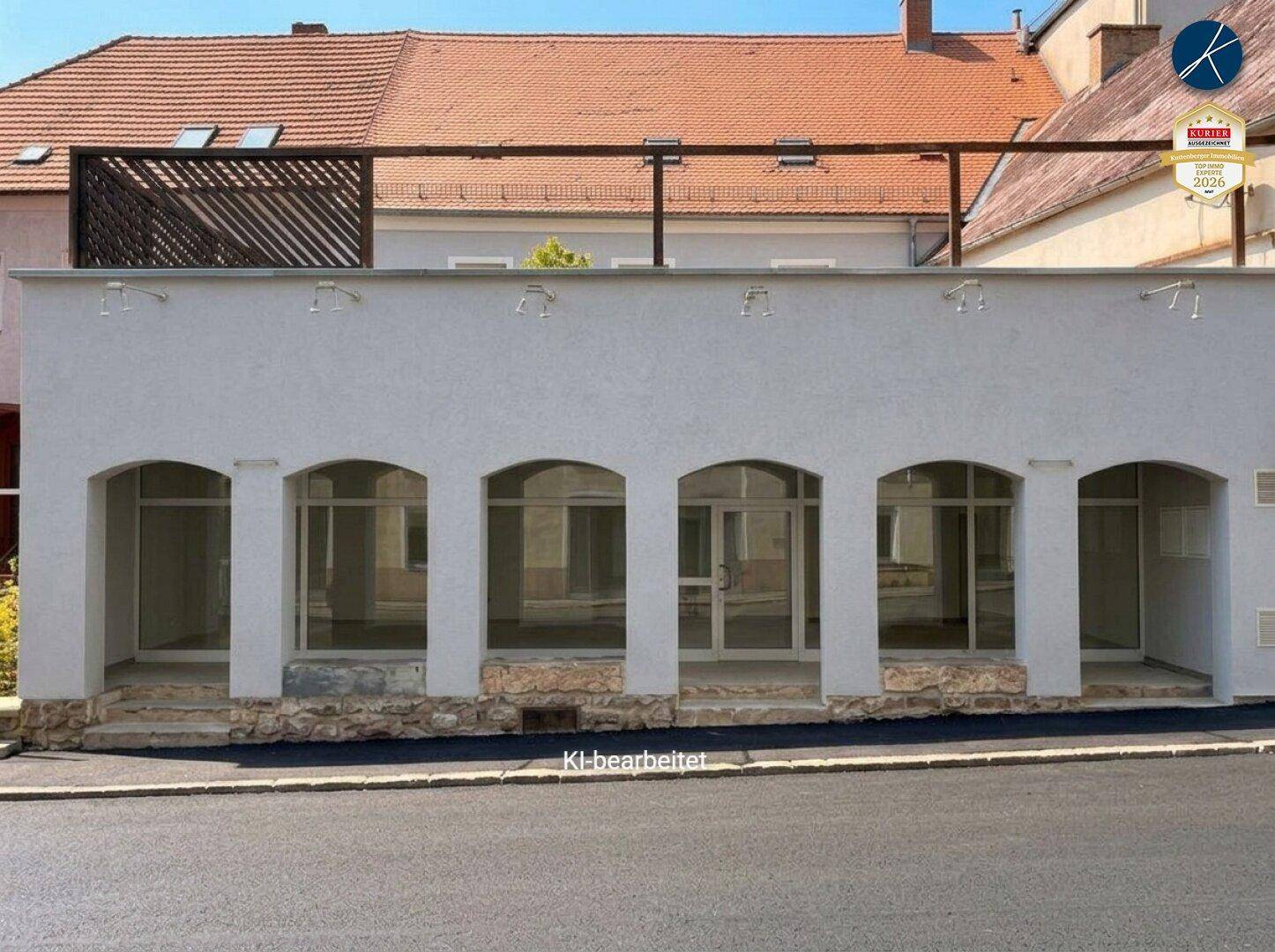 Außenansicht eines modernen Geschäftsgebäudes mit mehreren Bogenfenstern und einer Dachterrasse.