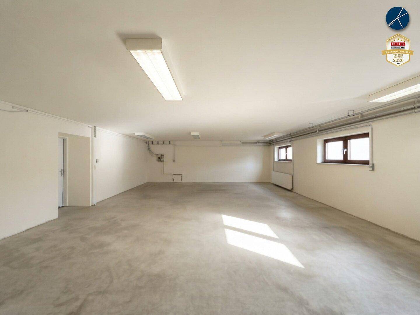 Heller Kellerraum mit Betonboden, mehreren Fenstern und einer Tür, geeignet für verschiedene Nutzungen.