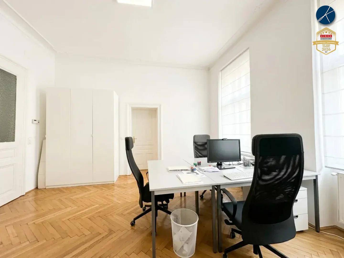 Modernes Büro mit integrierten weißen Schränken, Fischgrätparkett und viel natürlichem Licht.