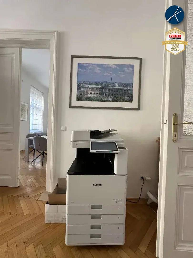 Flur mit einem großen Multifunktionsdrucker und Zugang zu weiteren Räumen, ausgestattet mit Parkettboden.