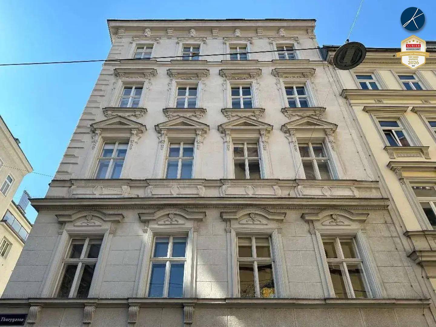 Klassische Fassade eines Altbaus mit vielen Fenstern und dekorativen architektonischen Details.