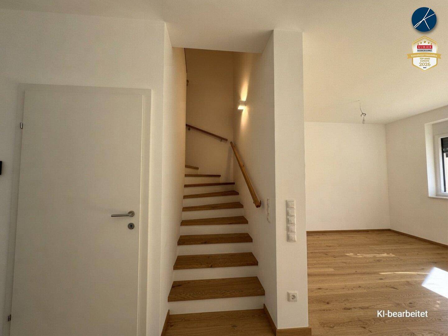 Heller Flur mit Holztreppe, die in die oberen Stockwerke führt.