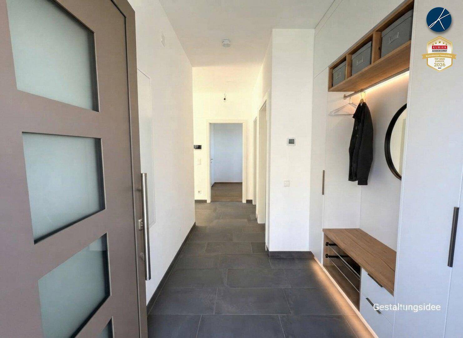 Moderner Eingangsbereich mit dunklen Fliesen, integrierter Garderobe und indirekter Beleuchtung.