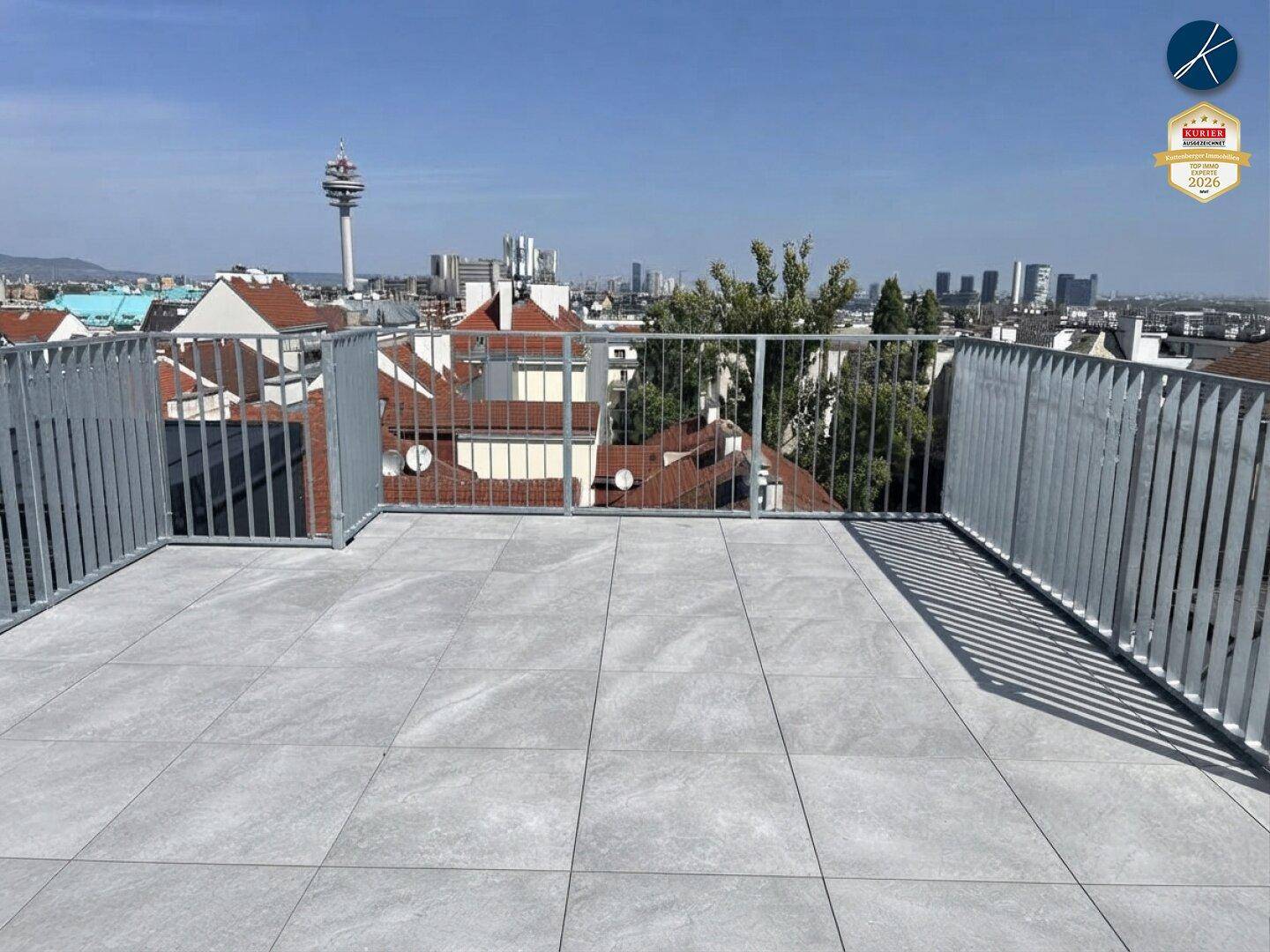 Große Dachterrasse mit Fliesenboden und Metallgeländer, bietet einen weiten Stadtblick.
