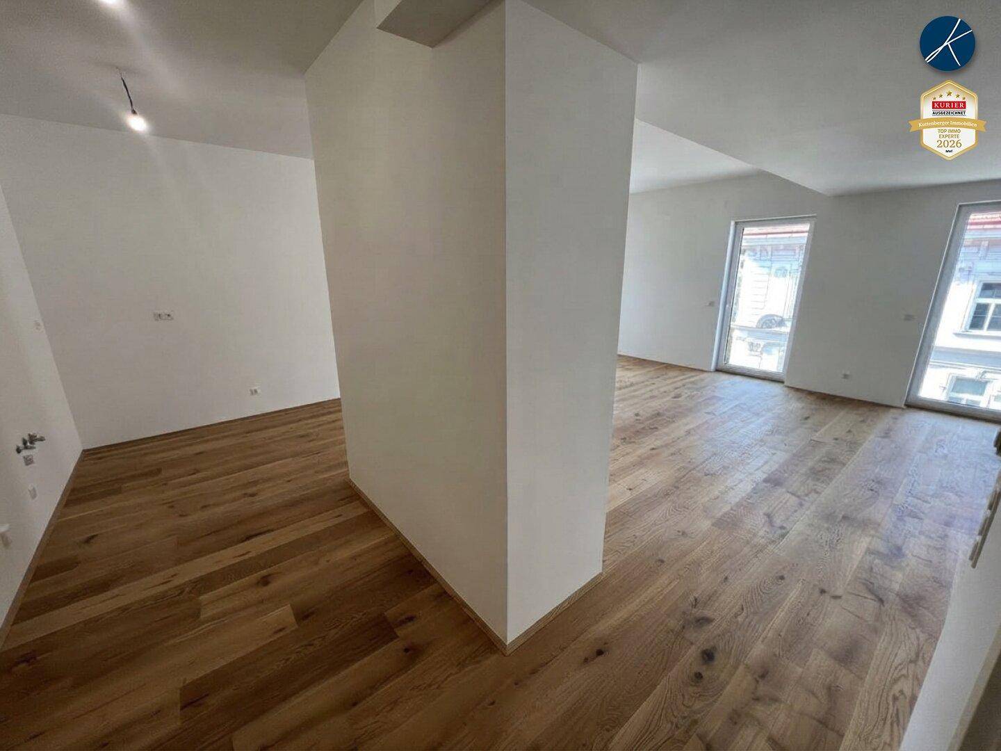 Geräumiger, heller Raum mit Holzboden und einem tragenden Pfeiler in der Mitte.