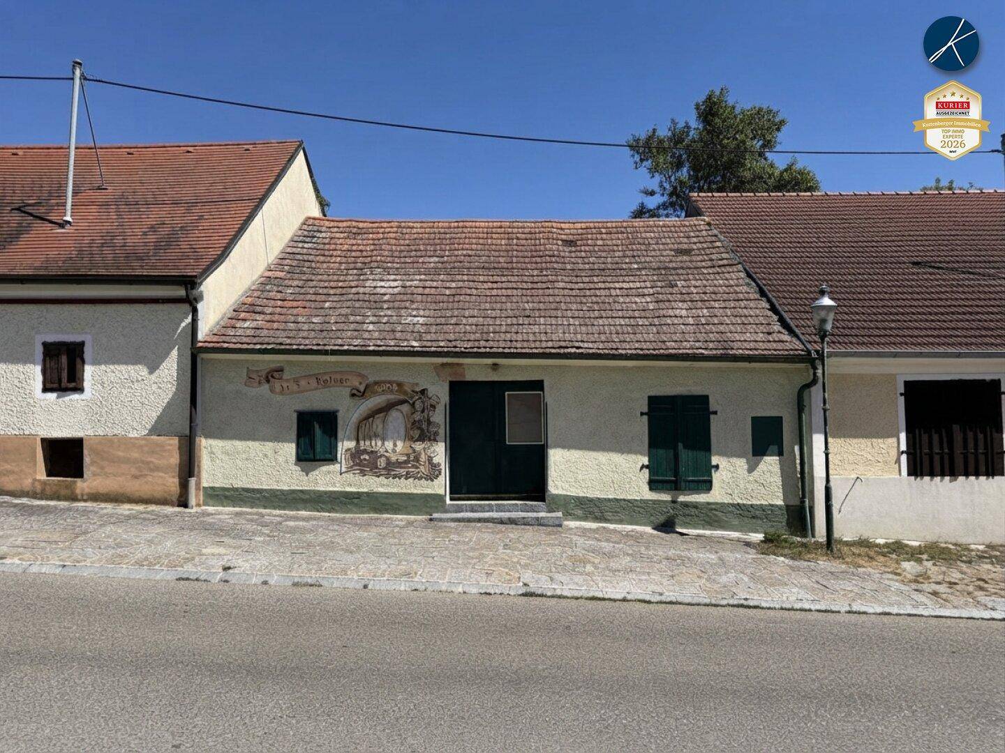 Fassade eines traditionellen Gebäudes mit Wandmalerei und grünen Fensterläden.
