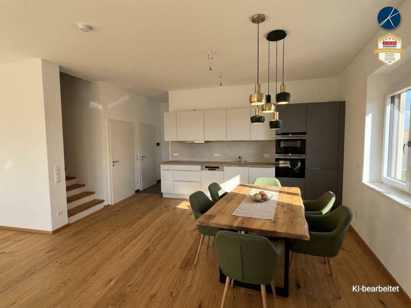 Offener Wohn- und Essbereich mit moderner Einbauküche, Holztisch und stilvollen Hängelampen.