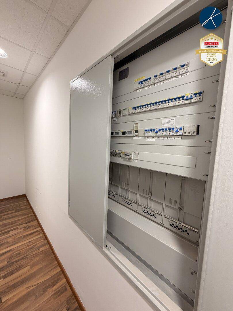 Offener Sicherungskasten an einer weißen Wand, der die elektrische Verteilung des Gebäudes zeigt.