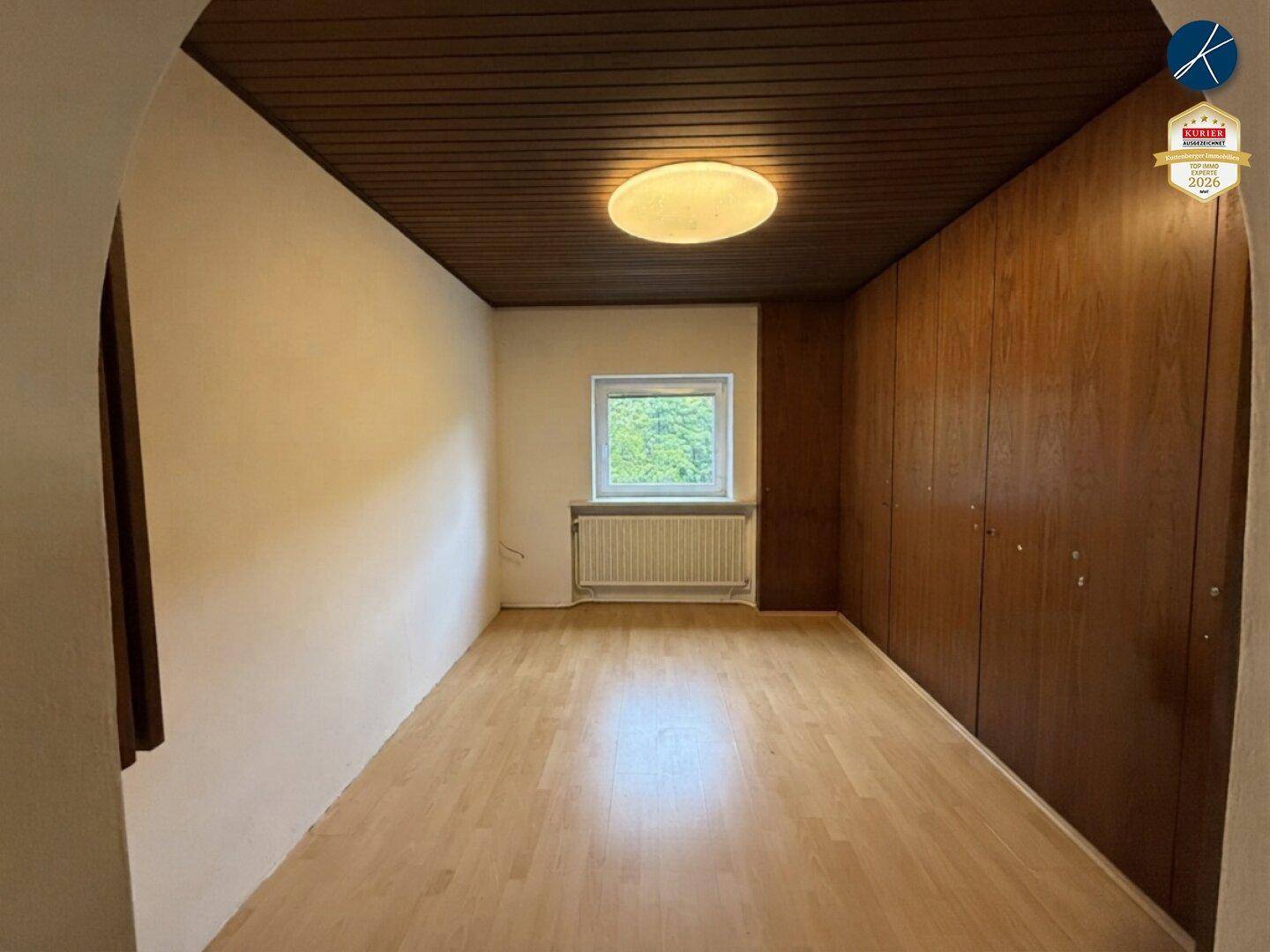 Schlafzimmer mit hellem Laminatboden, Holzdecke und großem Einbauschrank aus Holz.