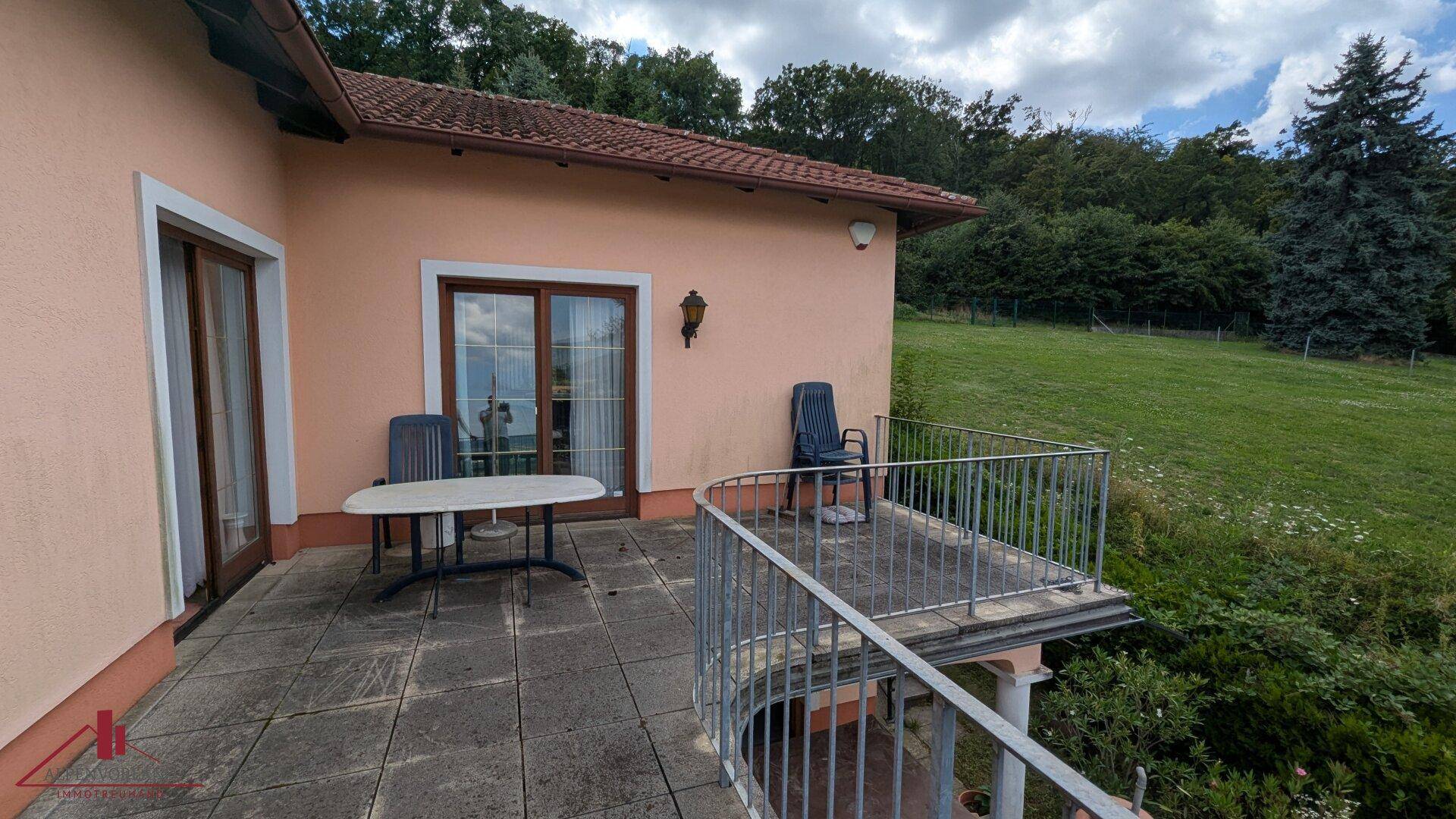 Geräumige Terrasse mit Fliesenboden und Blick ins Grüne, ideal für entspannte Stunden im Freien.