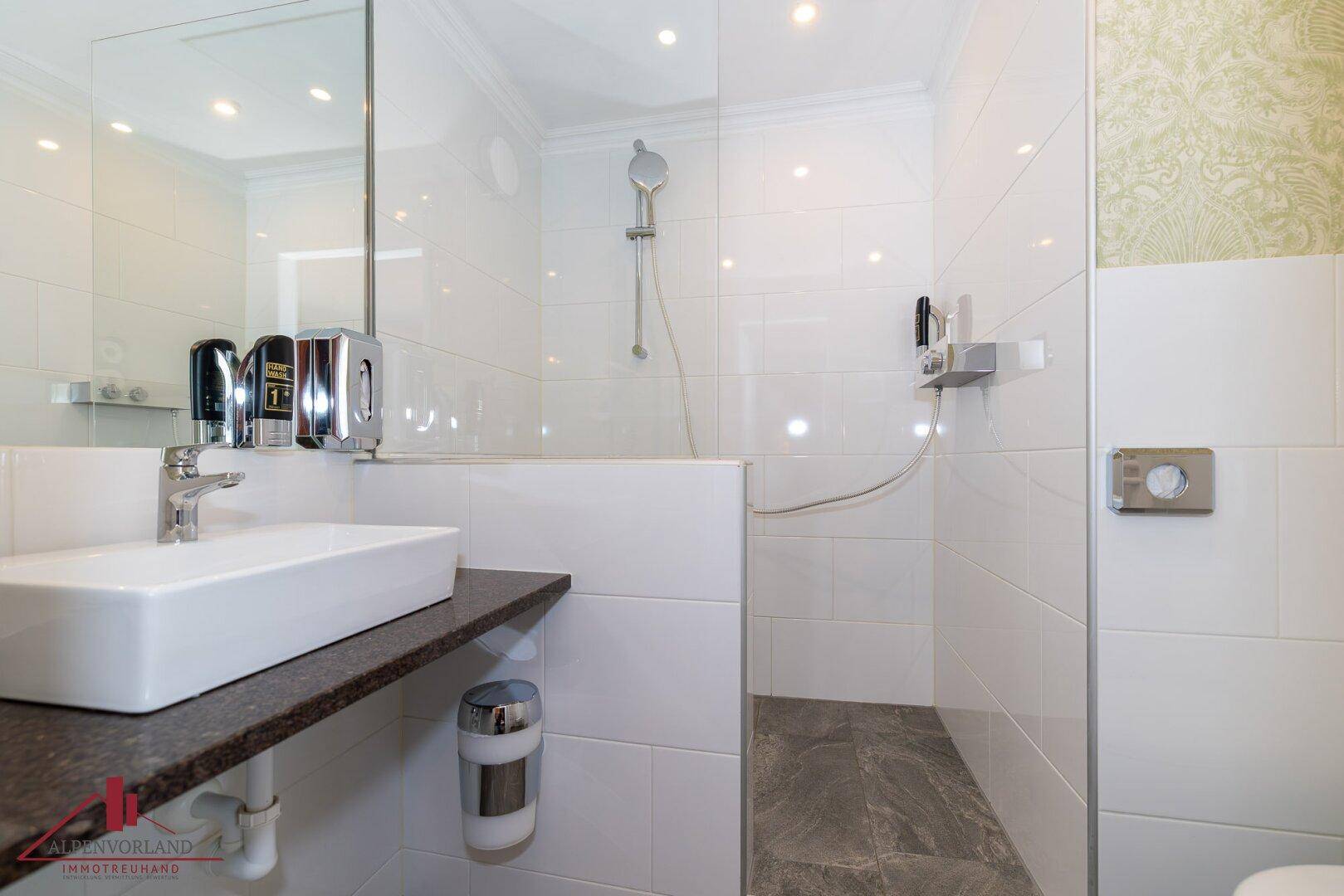 Modernes Badezimmer mit weiß gefliesten Wänden, ebenerdiger Dusche und Einzelwaschbecken.