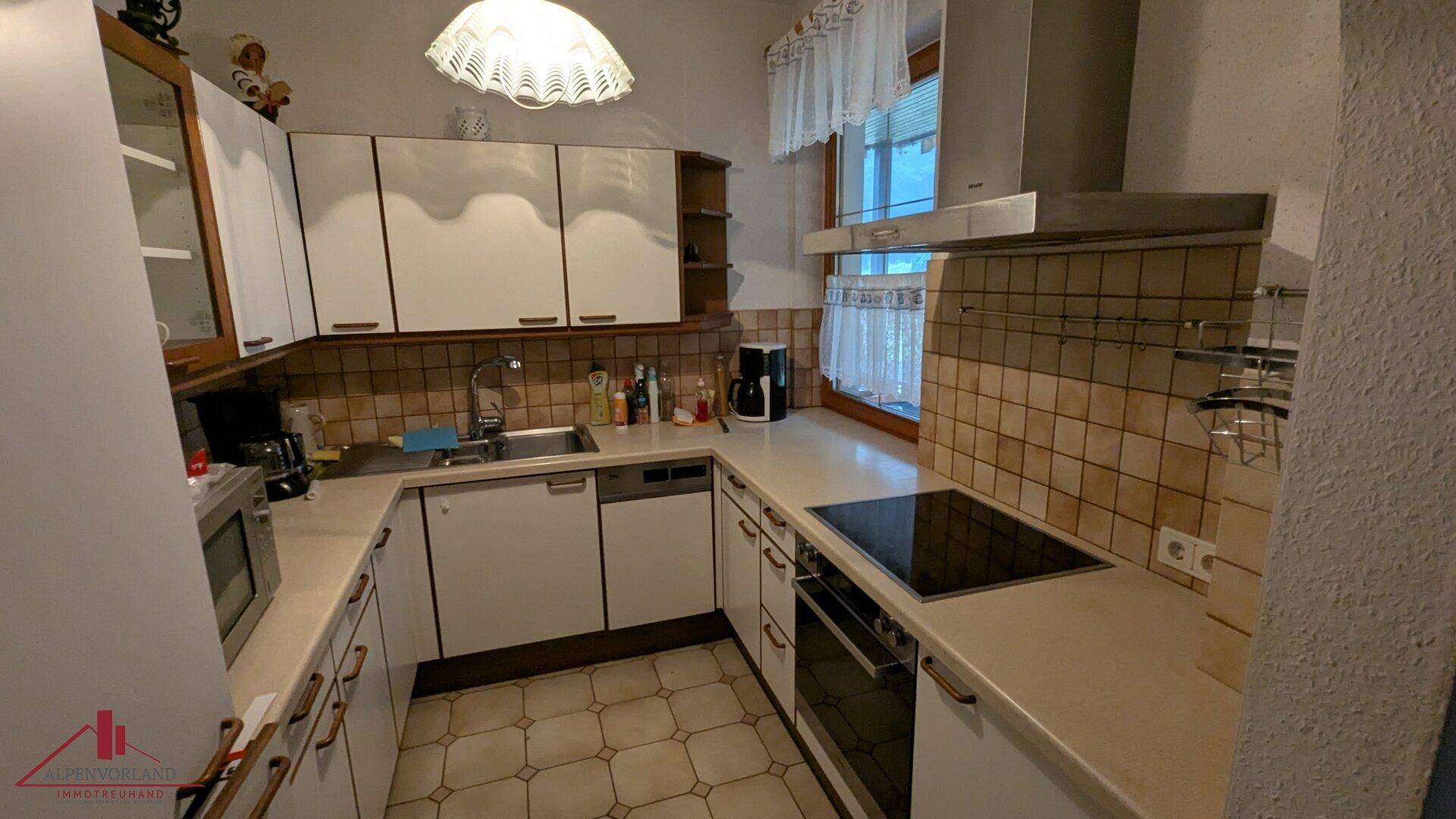 Helle Küche mit weißen Schränken, Fliesenboden und integrierten Geräten, ideal für den täglichen Gebrauch.