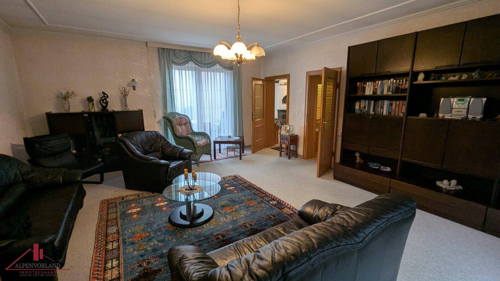 Klassisches Wohnzimmer mit bequemen Ledersofas, Teppichboden und großem Bücherregal.