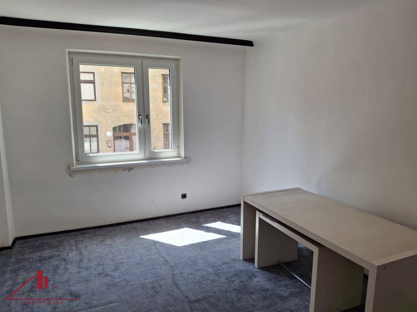 Freundliches Zimmer mit Fenster und einfacher Einrichtung, ideal als Schlaf- oder Arbeitsbereich.