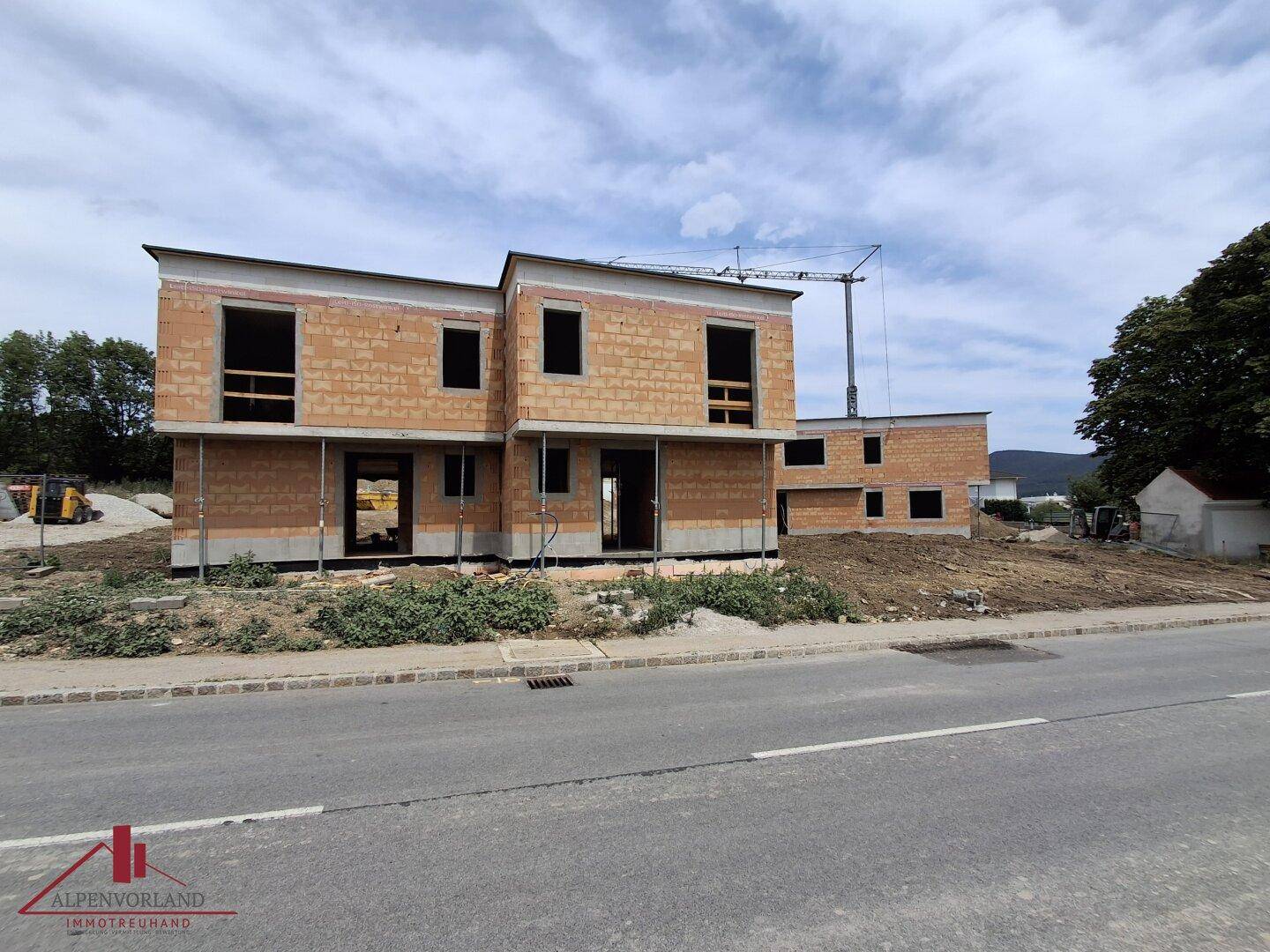 Baustelle mit zwei Rohbauten und einem Baukran, gesehen von der Straße aus.