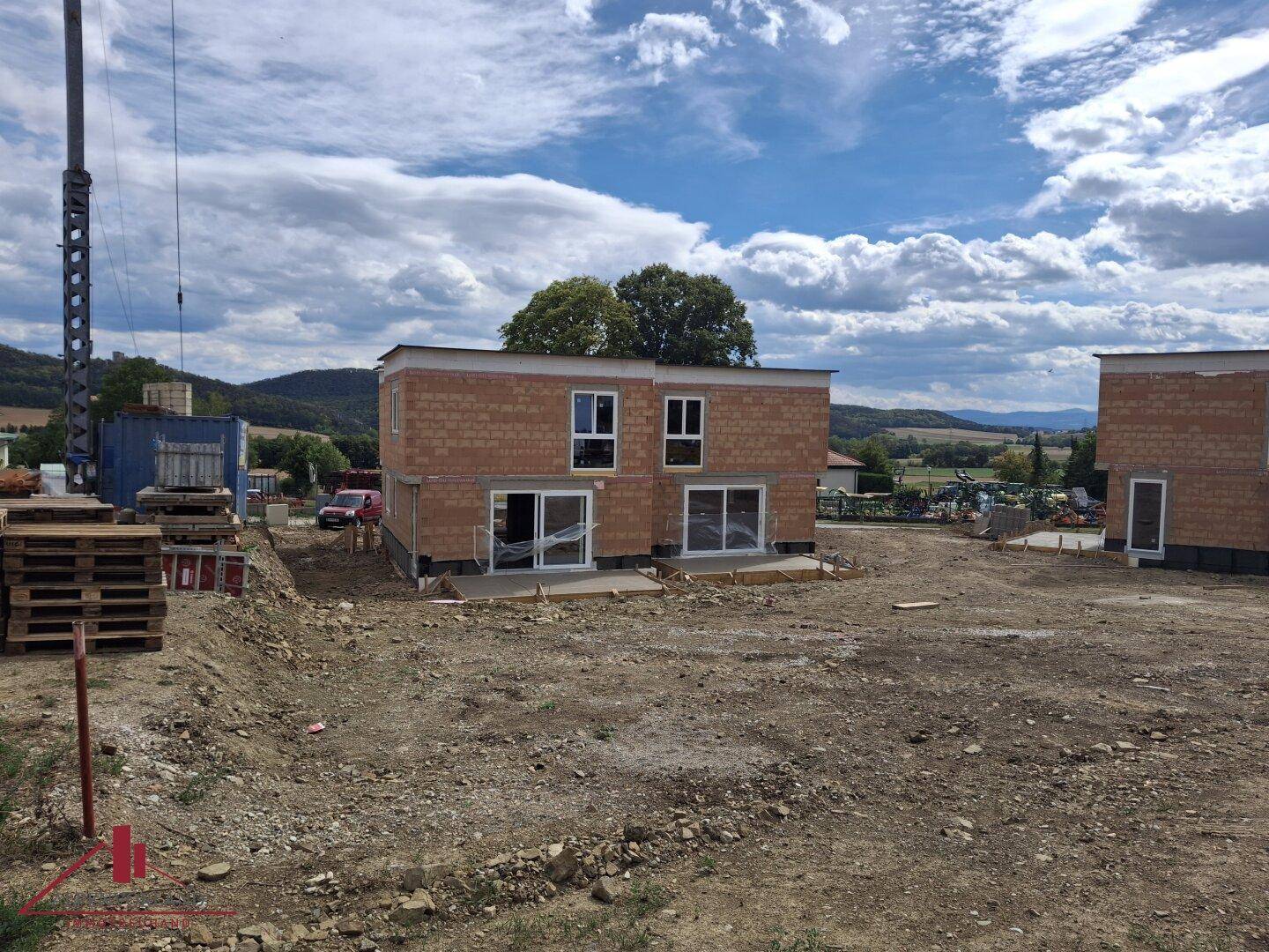 Neubau im Rohbauzustand mit bereits installierten Fenstern und Blick auf die umliegende Landschaft.