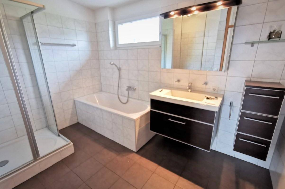 Gefliestes Badezimmer mit Badewanne, separater Dusche und modernem Waschtisch.