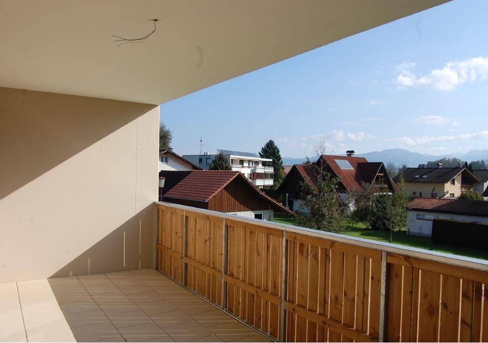 Geräumiger Balkon mit Holzbalkonbrüstung und weitem Blick über die Dächer und Berge.