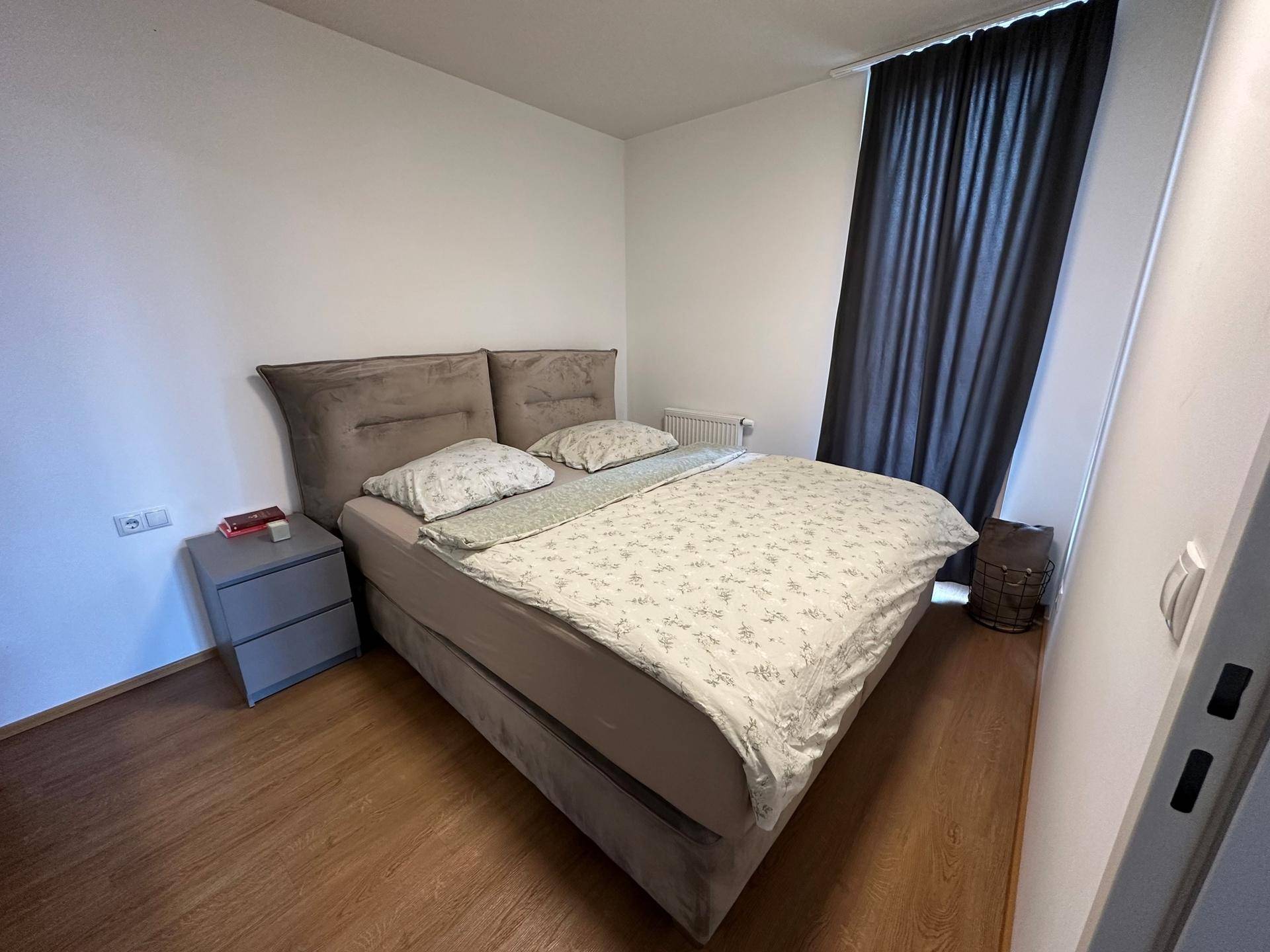 Gemütliches Schlafzimmer mit Doppelbett, Nachttischen und dunklen Vorhängen.
