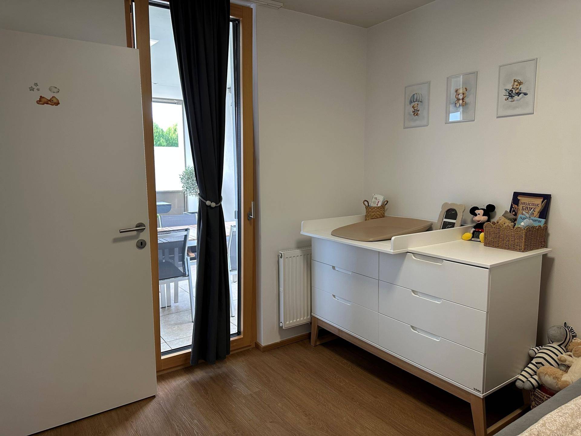 Helles Kinderzimmer mit Wickelkommode und direktem Zugang zu einem Außenbereich.