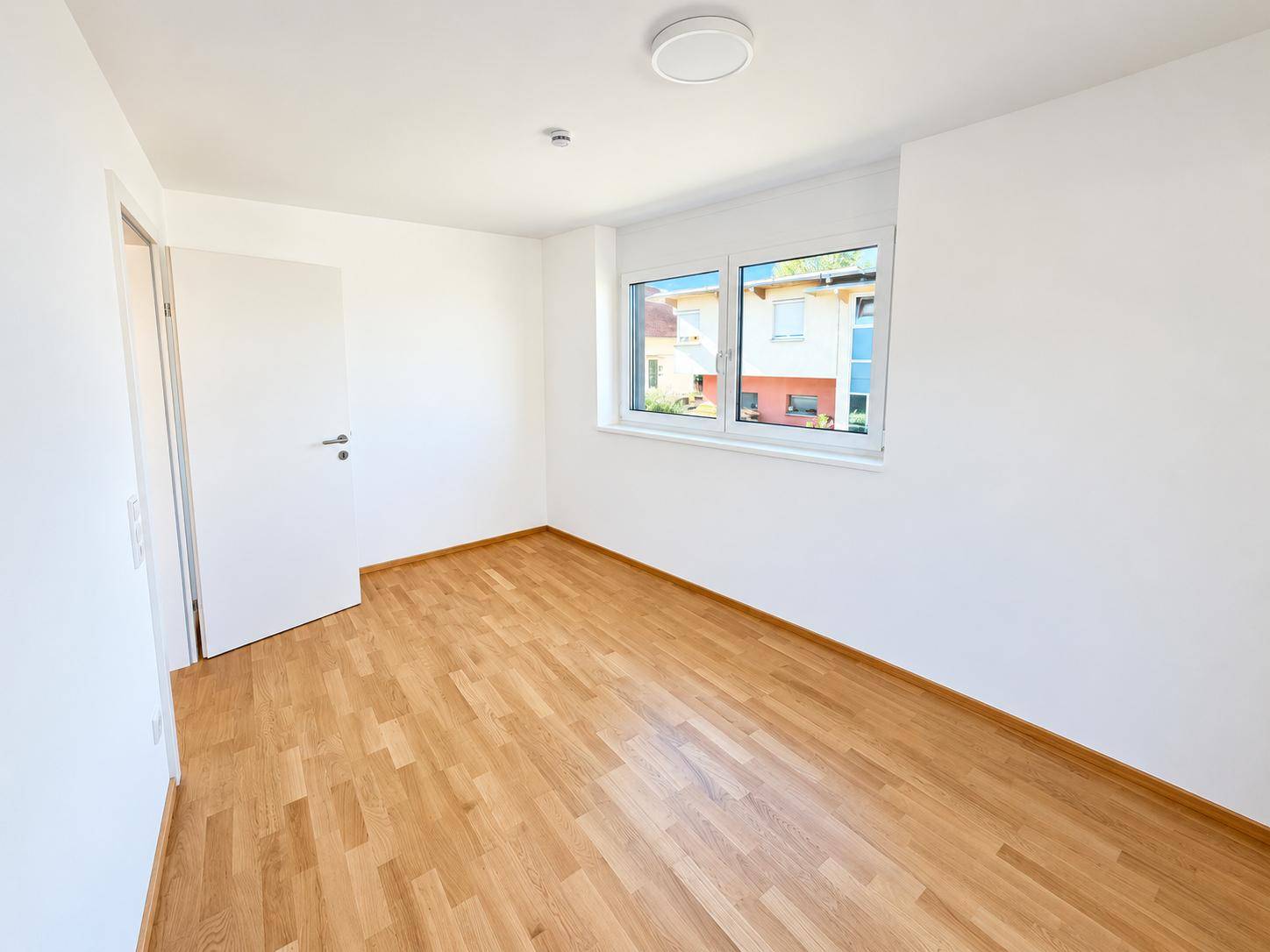 Geräumiges Zimmer mit Parkettboden und einem Fenster, das für eine angenehme Belichtung sorgt.