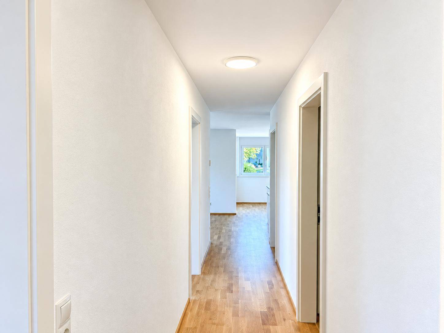 Langer, heller Flur mit Holzboden und Zugang zu verschiedenen Räumen.