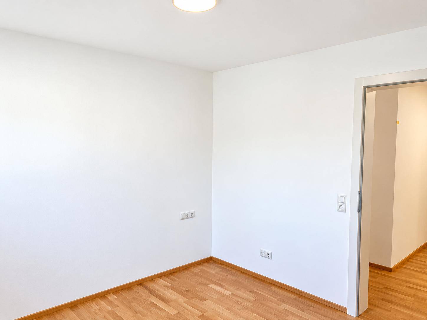 Geräumiges Zimmer mit Holzboden und Schiebetür, ideal als Schlaf- oder Arbeitszimmer.